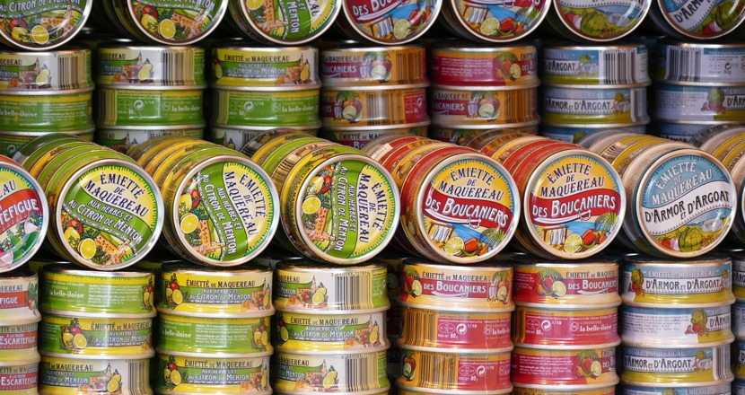 Konservburkar i färgsorterade rader. Foto.