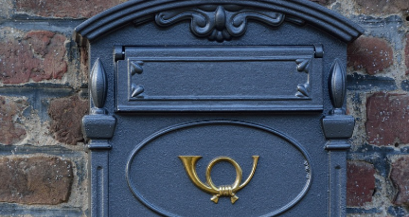 Blå postbox mot tegelvägg