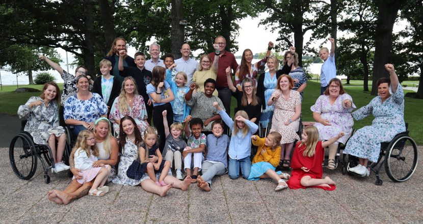 Gruppfoto med vuxna och barn utomhus.