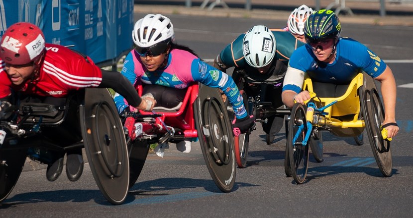 Paraidrottare i rullstolar i ett tävlingslopp. Foto.