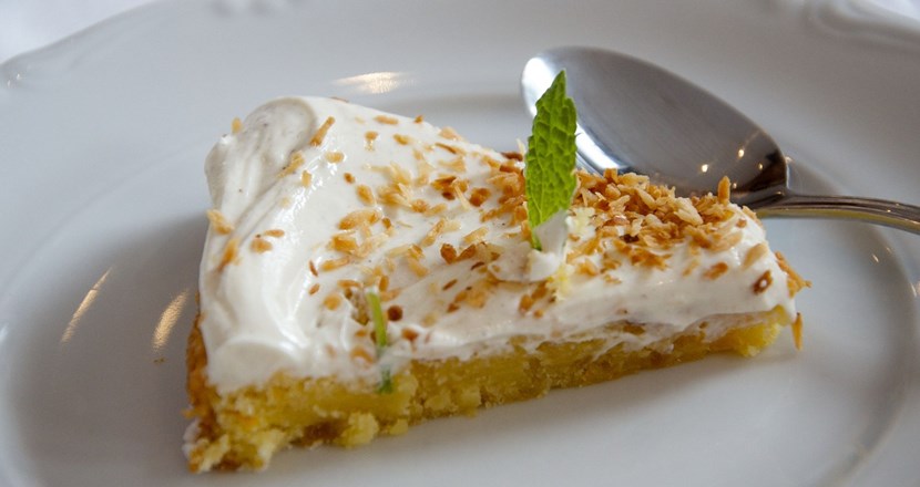 En bit cheesecake på en vit tallrik. Foto.