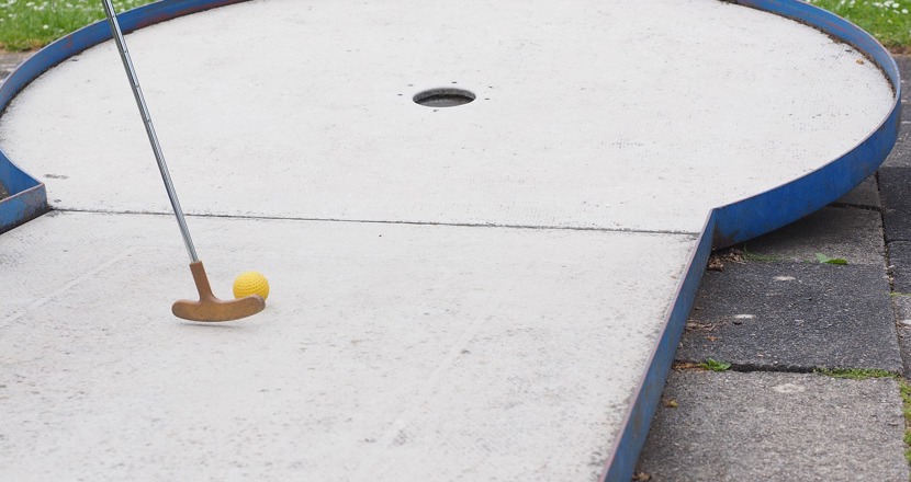 En vit bangolfsbana med en klubba och en gul boll. Foto.