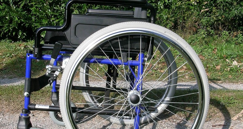 En blå och svart rullstol, som står på en väg med en grästräng i mitten. Foto.