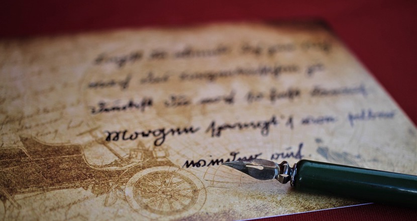 En gammal handskrift där spetsen på en bläckpenna ligger i nedre högra hörnet. Foto.