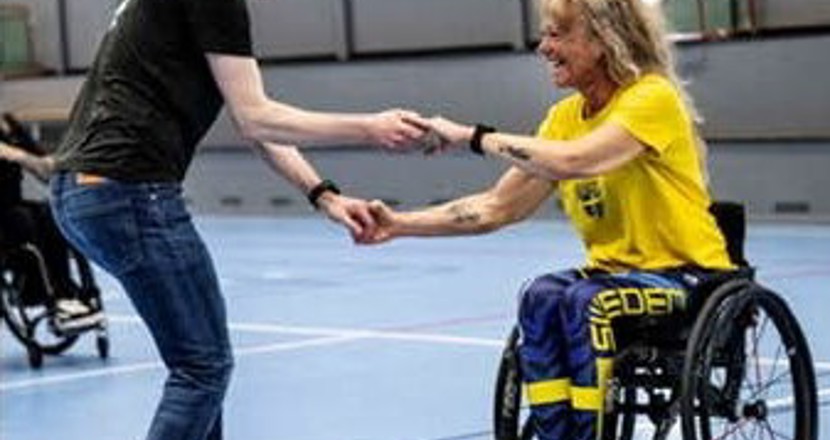 Ett par som dansar rullstolsdans - en stående man och en sittande kvinna. Foto.