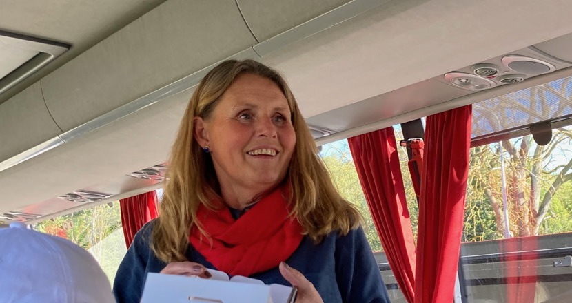 En kvinna med långt hår och röd scarfs guidar i en buss