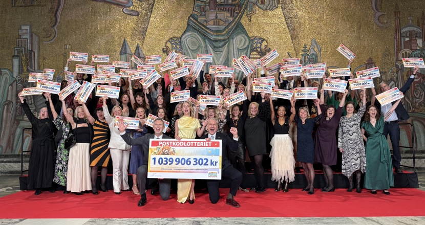 Gruppfoto med glada festklädda människor som håller upp checkar. Foto,