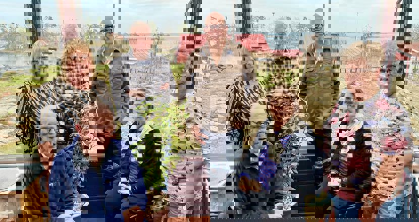 En bild på sex personer uppställa med sjöutsikt bakom. Tre kvinnor och Tre män