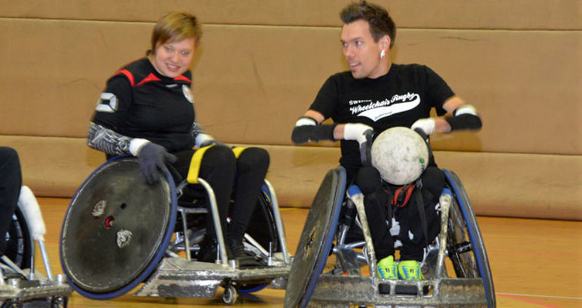 Två personer i rullstol, den ena med en boll i knät.