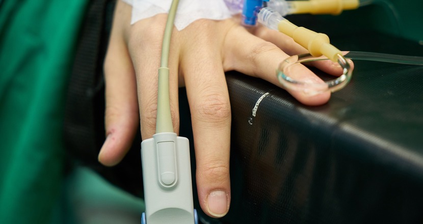 En hand med en syremätare på ett operationsbord