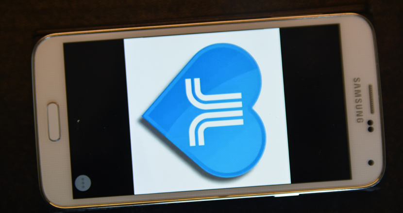 En mobiltelefon med ett blått hjärta med Stockholms läns landstings logotyp. Foto.