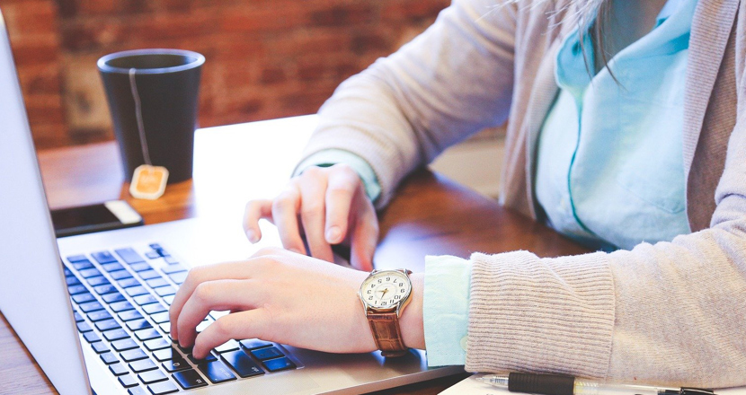 Person som skriver på sin dator och dricker te