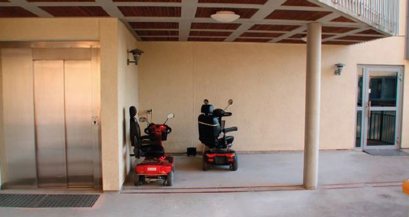 En betongyta bredvid en port, delvis under tak, bredvid en hiss. Foto.