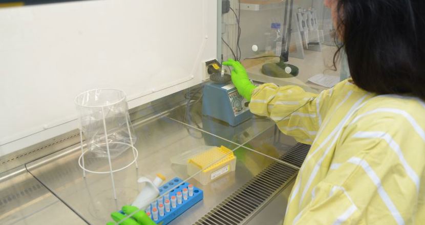 En person i skyddskläder som jobbar vid ett dragskåp. Foto.