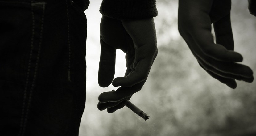Svartvitt foto med två händer. En hand håller i en cigarett.