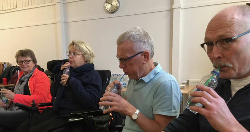 Fyra personer som blåser i flaskor med sugrör.