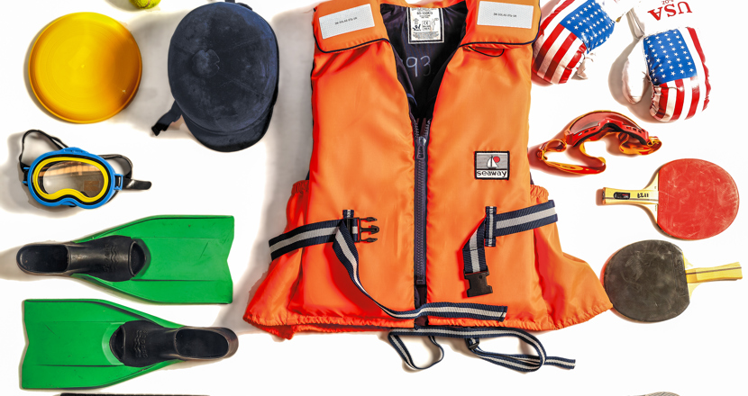 Ett antal fritidsprylar, till exempel en orange flytväst, två pingisracketar - en svart och en röd och två gröna simfötter. Foto.