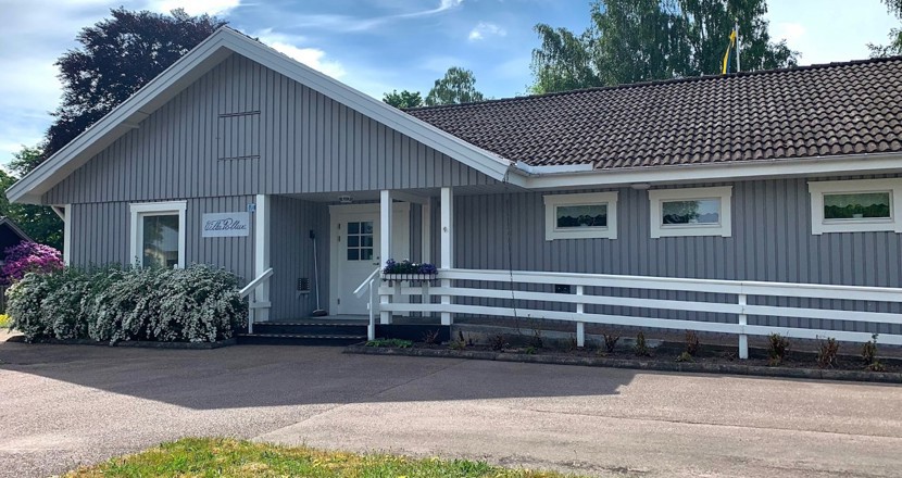 En grå villa i träpanel med en vit ramp längs fasaden. Foto.