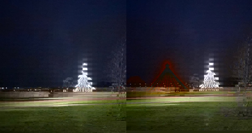 En kvällsbild med en julgran av ljusslingor och en lysande toppstjärna. 