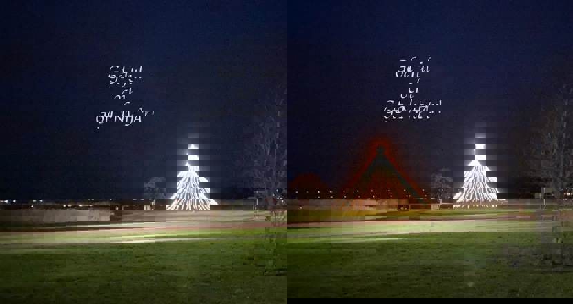 En kvällsbild med en julgran av ljusslingor och en lysande toppstjärna. Text: God jul o gott nytt år