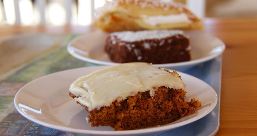 Närbild på kakbitar som ligger på tallrikar på en bricka som står på ett bord. Foto.